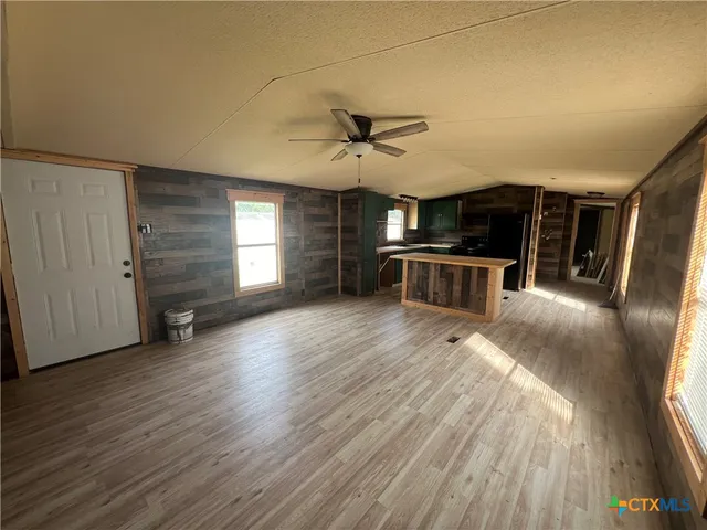 a view of a kitchen with furniture a ceiling fan and wooden floor