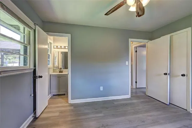 an empty room with wooden floor cabinet and windows