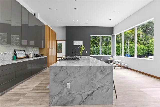 a view of a kitchen with kitchen island a large window cabinets and living room view