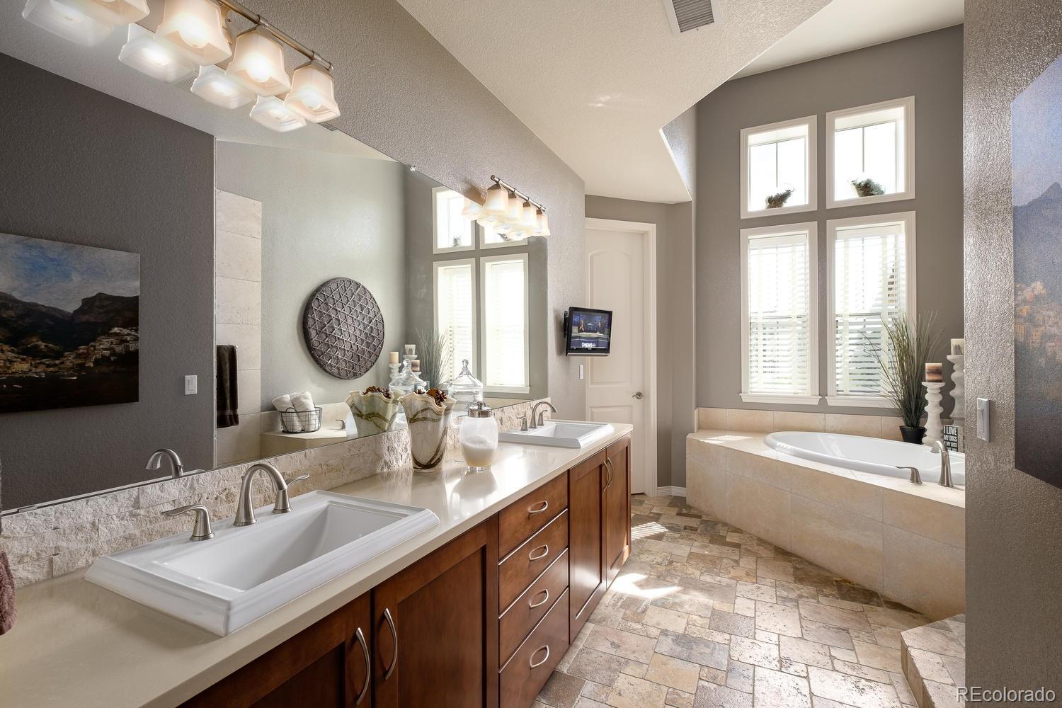 9367 Viaggio Way Highlands Ranch, CO 80126 - Photo 8 of 9 a bathroom with a tub a double vanity sink and a mirror