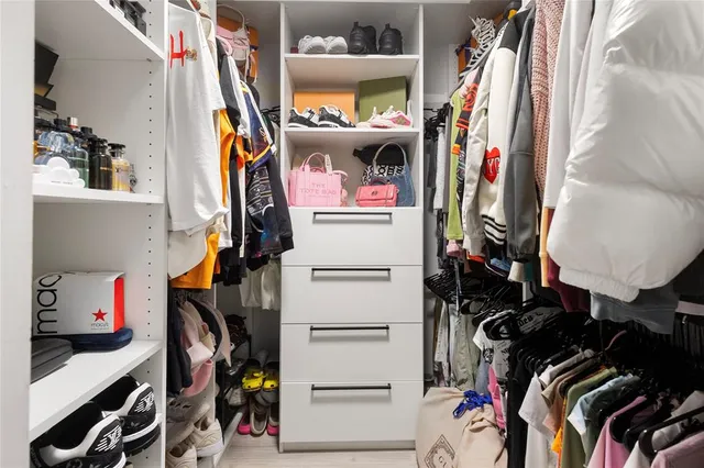 a view of walk in closet with clothes and shoes