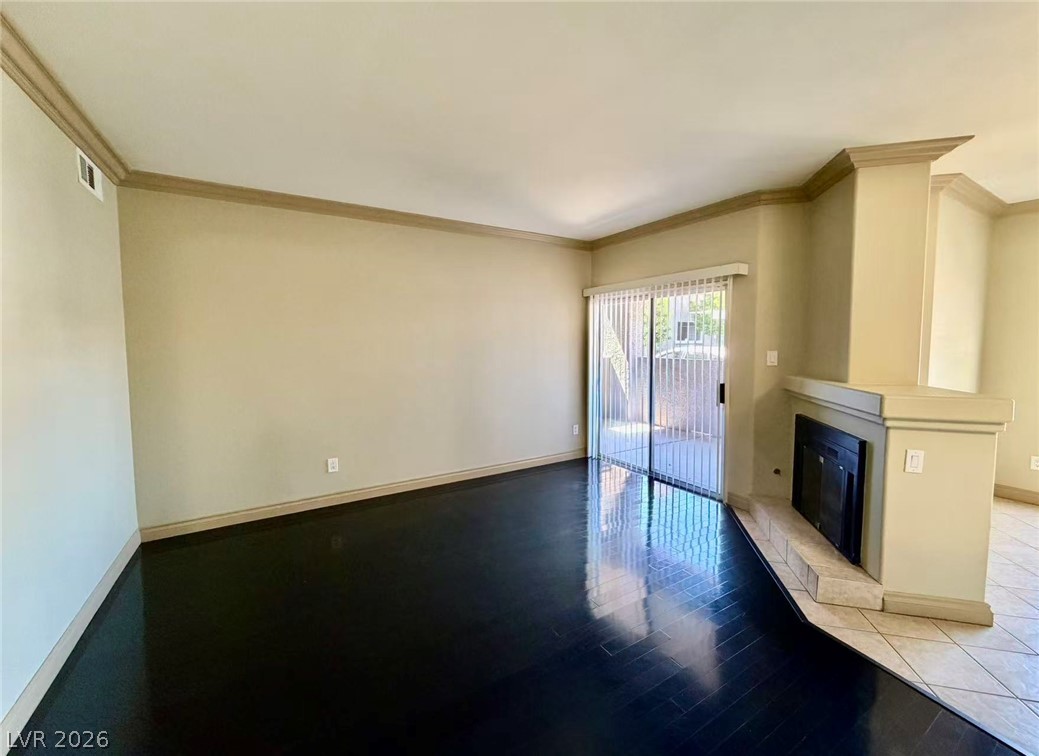5525 West Flamingo Road, Unit 1019 Las Vegas, NV 89103 - Photo 7 of 18 Hardwood flooring extends into a spacious living area, complete with a cozy fireplace and sliding glass door access.