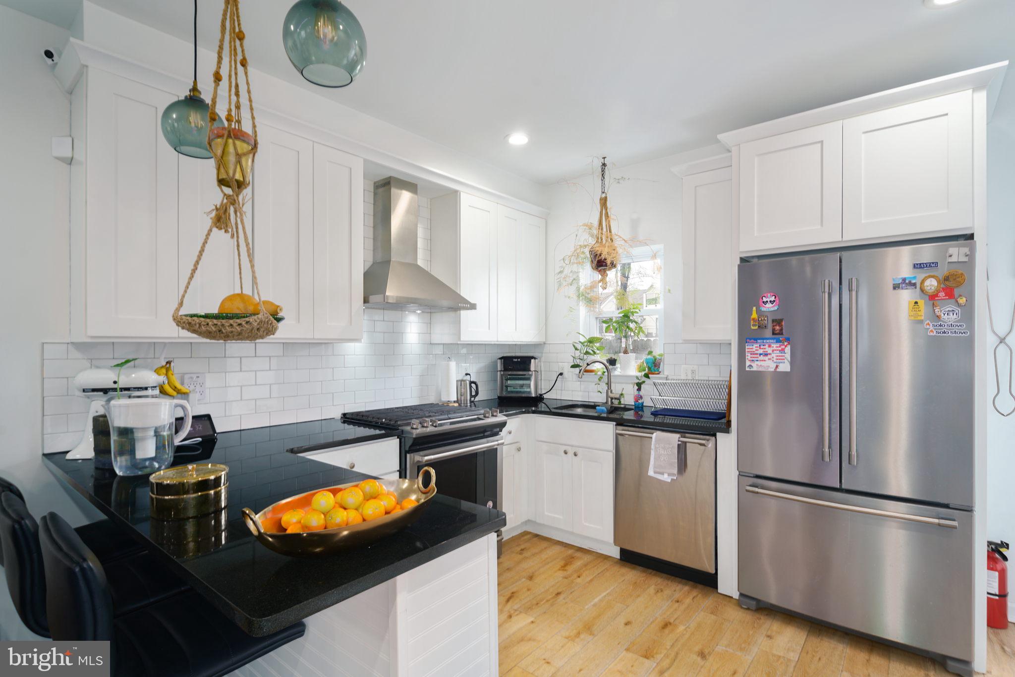 3045 Baltz Street Philadelphia, PA 19121 - Photo 5 of 18 a kitchen with stainless steel appliances granite countertop a refrigerator a sink dishwasher a stove and a dining table with wooden floor