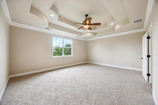 an empty room with chandelier fan and windows