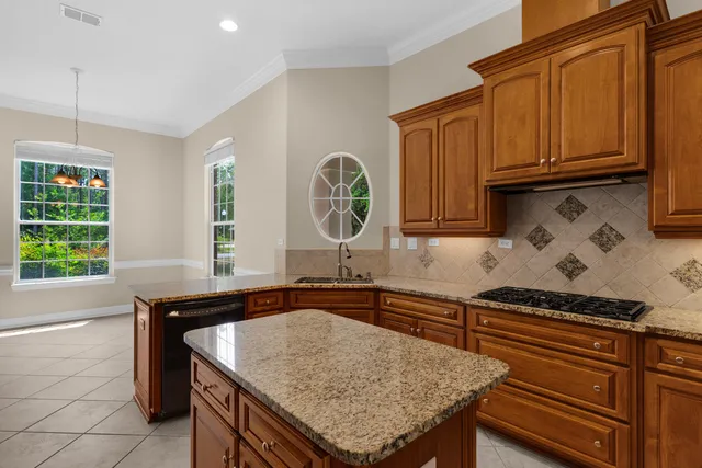a kitchen with stainless steel appliances granite countertop a sink a stove and a wooden cabinets