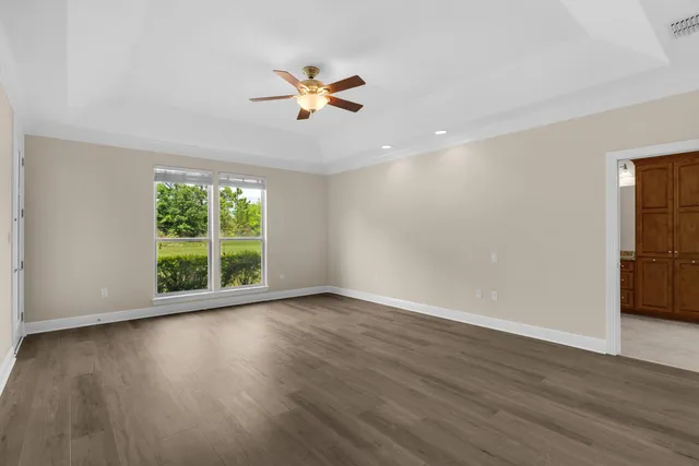 a view of an empty room with wooden floor and window