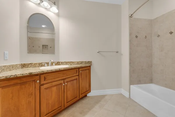 a bathroom with a granite countertop sink mirror and bathtub