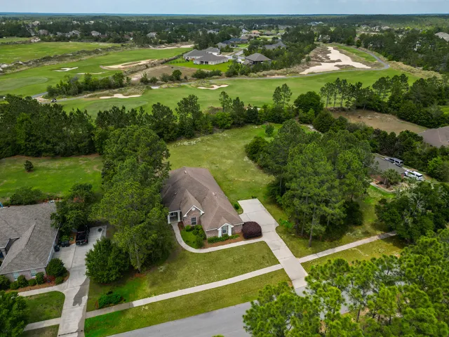 an aerial view of a residential houses with outdoor space and trees