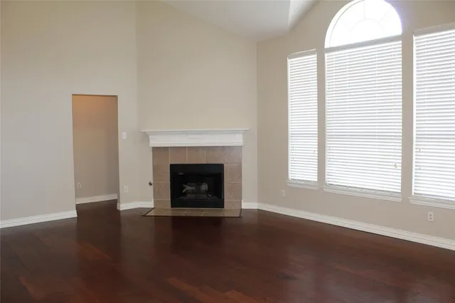 an empty room with wooden floor a fireplace and windows