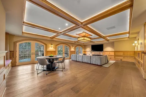 a living room with couches a flat tv screen and a dining table with wooden floor