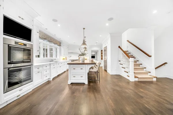 a kitchen with stainless steel appliances kitchen island granite countertop a stove and a wooden floors