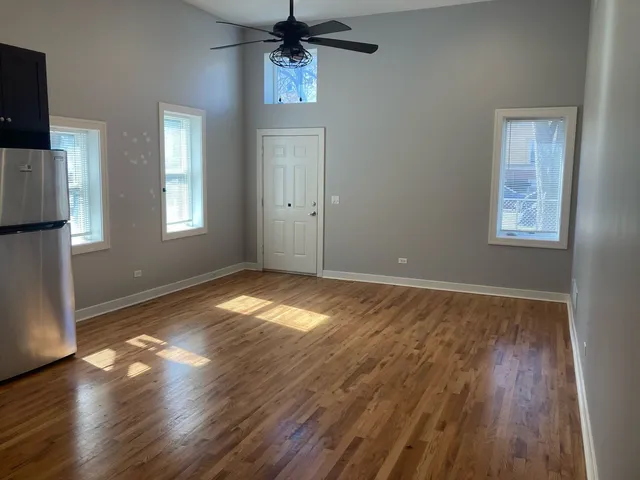 an empty room with wooden floor cabinet and windows