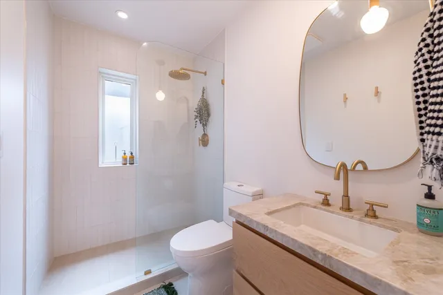 a bathroom with a granite countertop sink mirror vanity and toilet