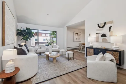 a living room with furniture kitchen view and a large window
