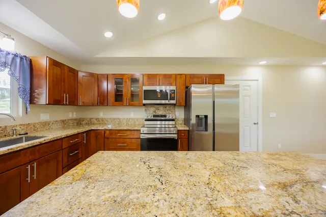 a kitchen with stainless steel appliances granite countertop a refrigerator and a stove top oven