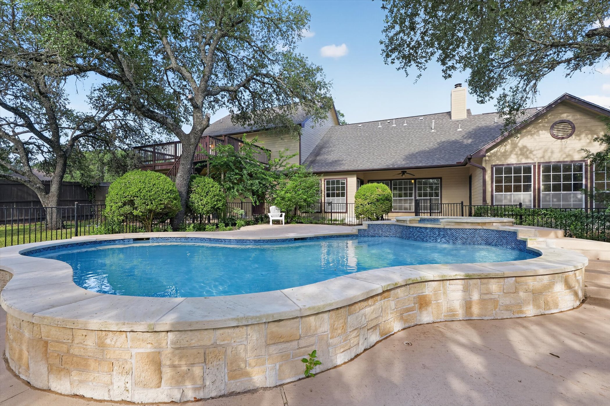13615 Copperleaf Trail Manchaca, TX 78652 - Photo 32 of 38 An inviting backyard oasis offers a sparkling pool with an integrated spa, set against a backdrop of mature trees and a spacious home.