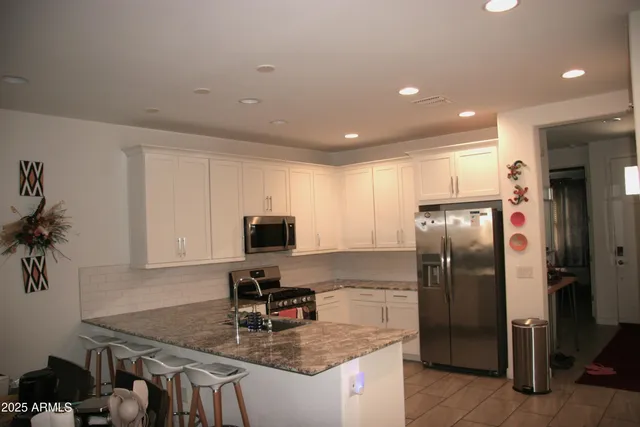 a kitchen with stainless steel appliances granite countertop a refrigerator a stove and a sink