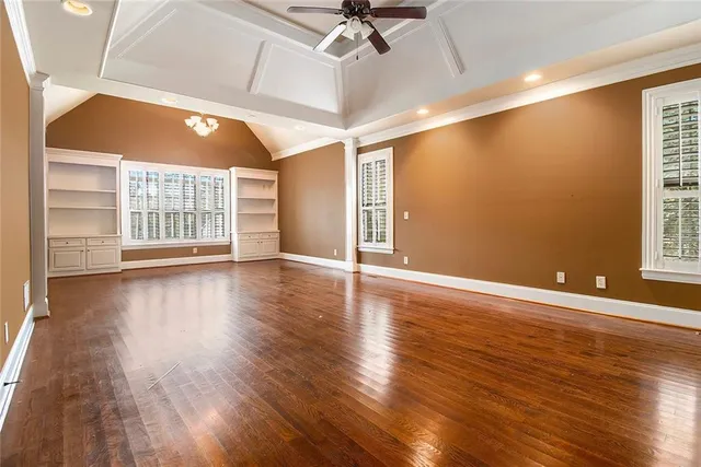 a view of an empty room with a window and wooden floor