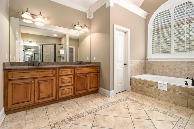 a spacious bathroom with a granite countertop sink a mirror a bathtub and next to a window