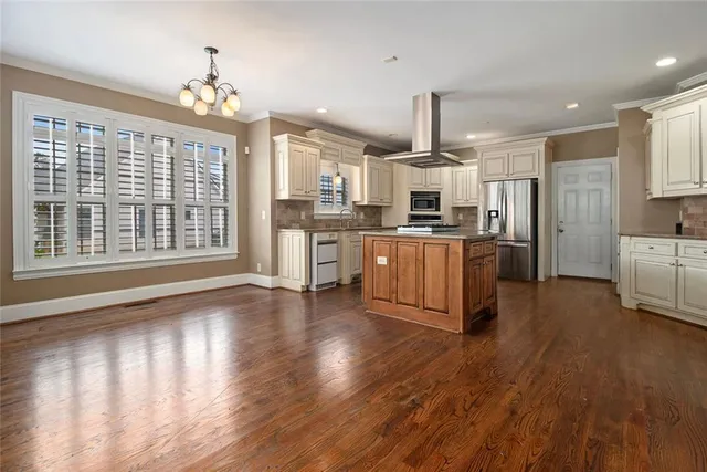 a large kitchen with cabinets wooden floor and stainless steel appliances