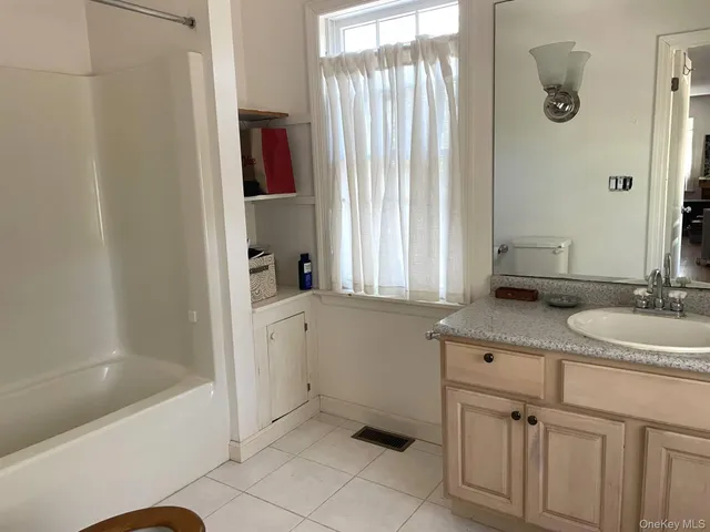 a bathroom with a granite countertop sink and a bathtub