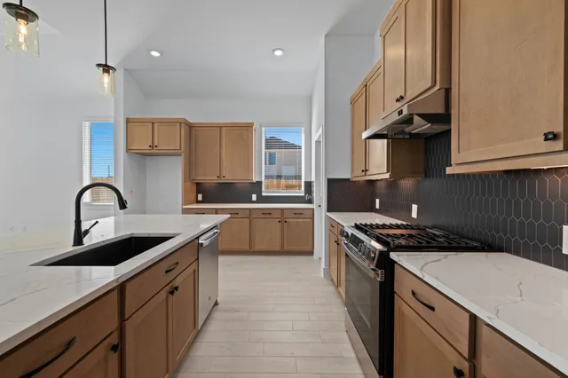 a kitchen with stainless steel appliances granite countertop a sink stove and cabinets