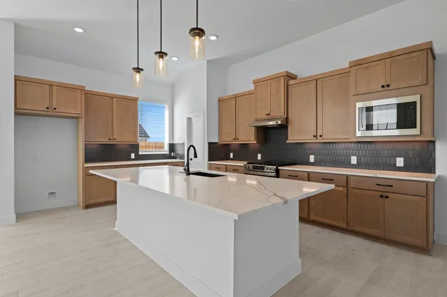 a large kitchen with cabinets appliances a sink and a counter top space