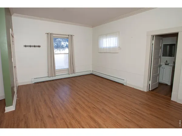 a view of an empty room with wooden floor and window