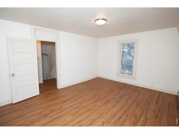 an empty room with wooden floor and chandelier fan