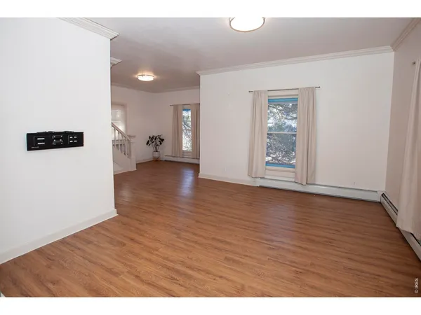 a view of an empty room with window and wooden floor