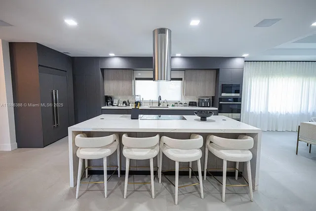 a kitchen with stainless steel appliances granite countertop a sink a stove a refrigerator and chairs