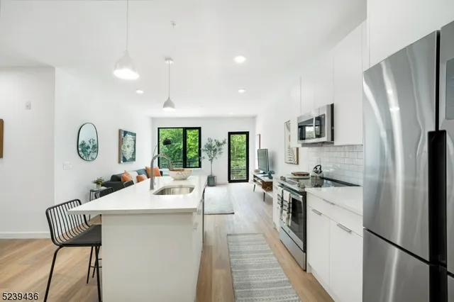 a kitchen with stainless steel appliances granite countertop a refrigerator a sink dishwasher a stove with white cabinets and wooden floor