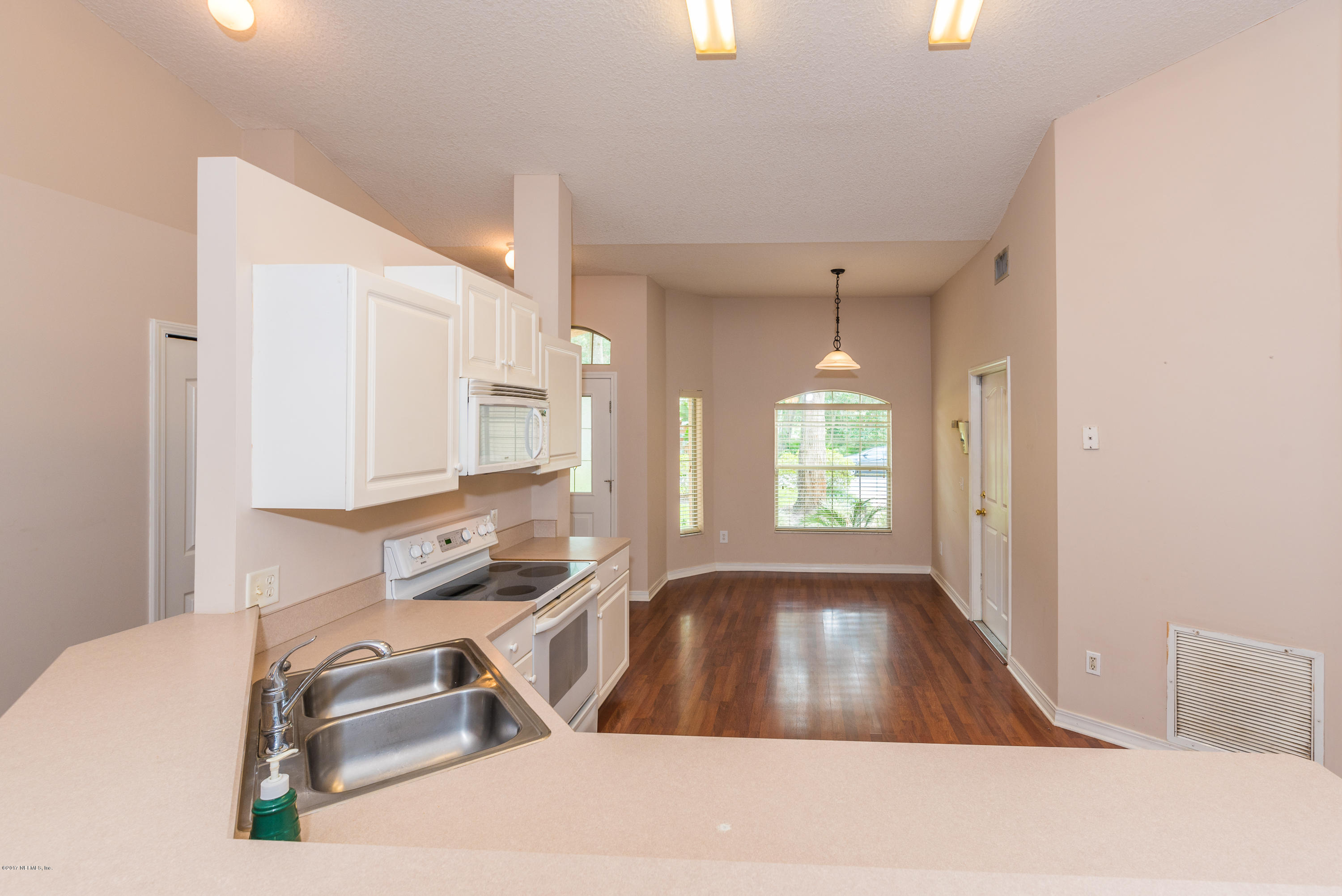 444 Orchis Road St. Augustine, FL 32086 - Photo 13 of 56 a view of a kitchen with kitchen island a sink wooden floor and a window
