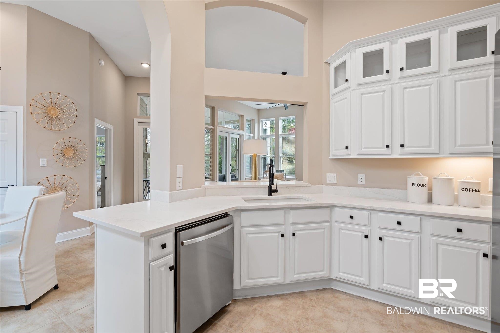 9259 Genipa Way Gulf Shores, AL 36542 - Photo 17 of 72 Kitchen featuring sink, light tile patterned floors, stainless steel dishwasher, kitchen peninsula, and white cabinets