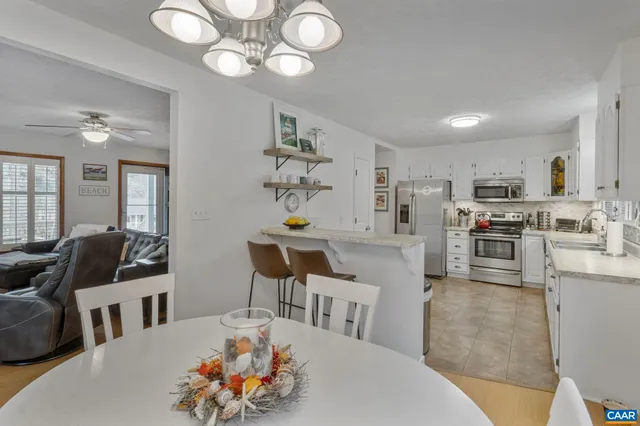 a living room with furniture kitchen view and a chandelier