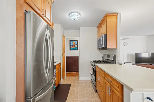 a kitchen with stainless steel appliances granite countertop a refrigerator a stove and a sink