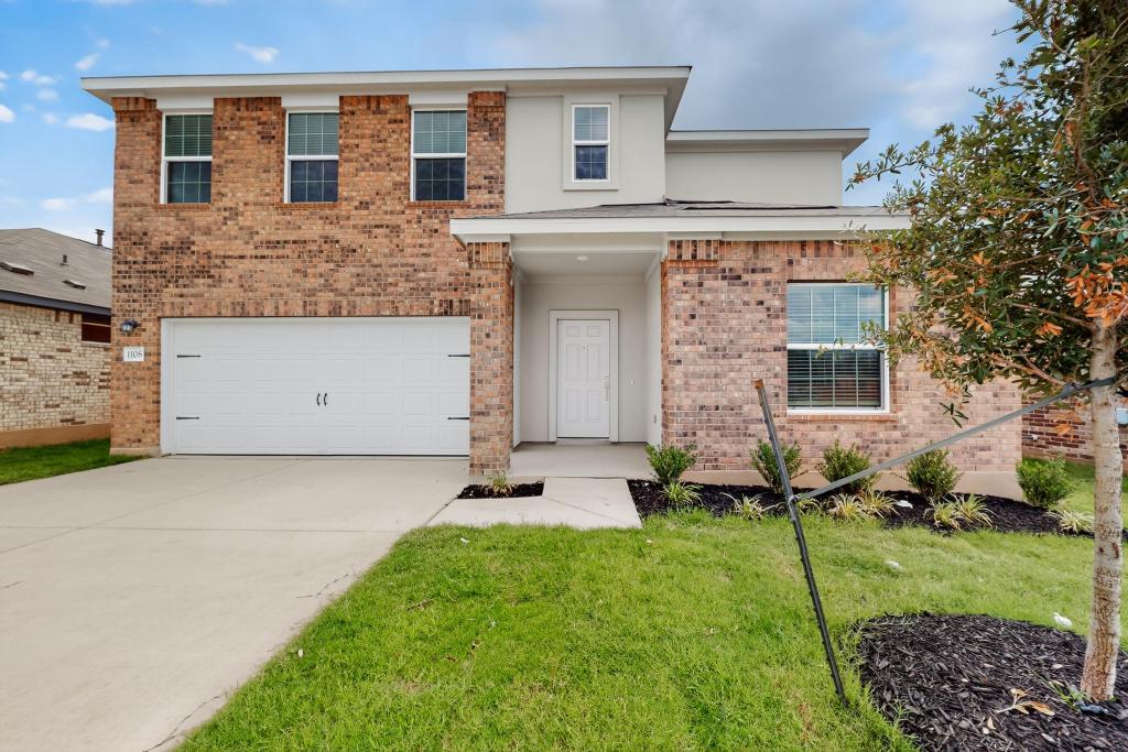 Traditional-style home with brick siding, concrete driveway, a garage, and a front lawn