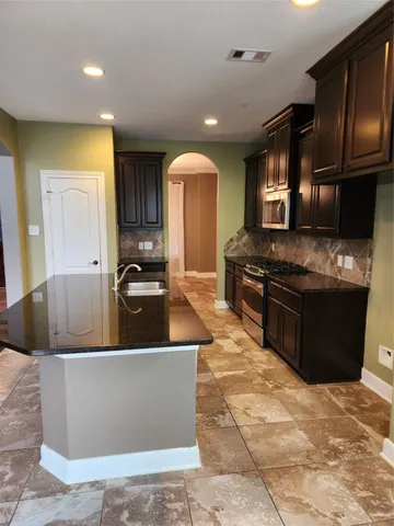 a kitchen with stainless steel appliances granite countertop a sink a stove and a refrigerator
