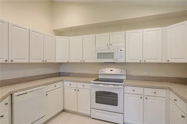 a kitchen with white cabinets and white appliances