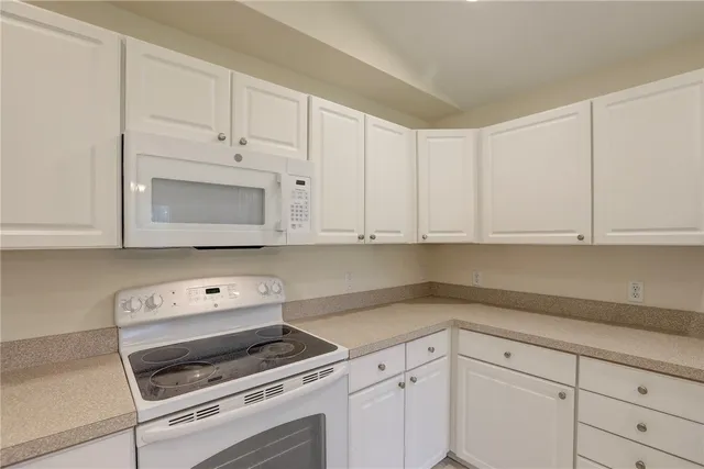 a kitchen with granite countertop white cabinets and window