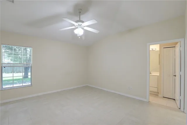 an empty room with a chandelier fan and windows