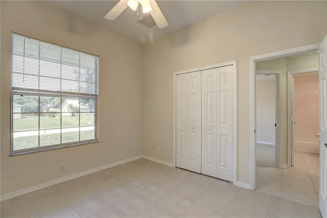 an empty room with windows and fan