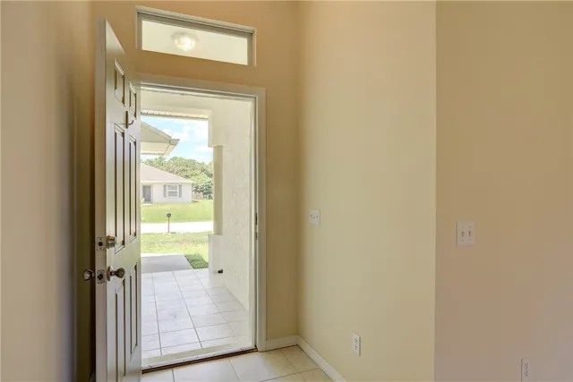 an empty room with chandelier fan and windows