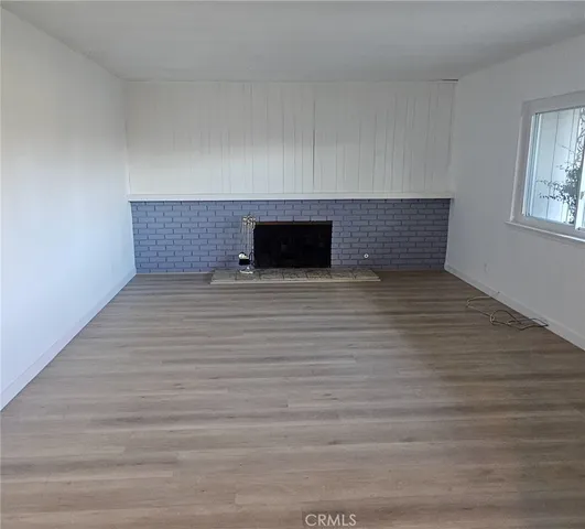a view of empty room with wooden floor and fireplace