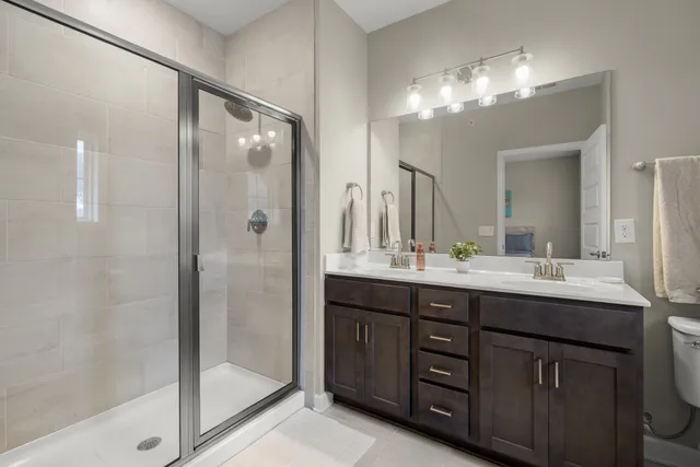 a bathroom with a double vanity sink mirror and shower
