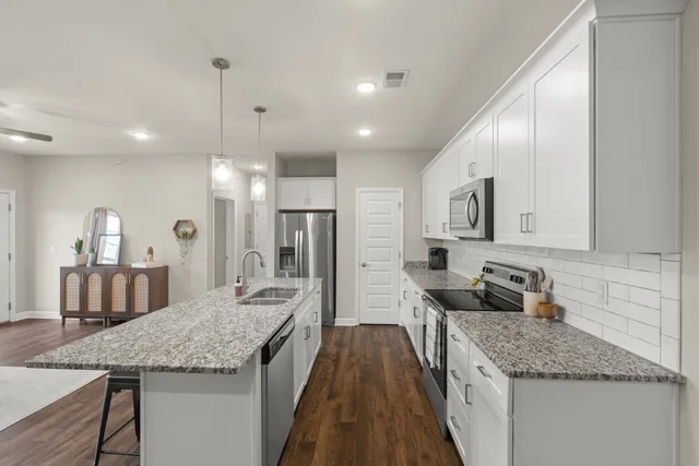 a kitchen with stainless steel appliances granite countertop a sink stove and refrigerator