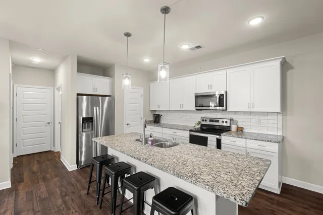 a kitchen with stainless steel appliances granite countertop a stove refrigerator a sink dishwasher with a dining table and chairs