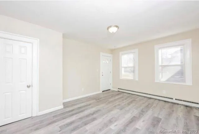 an empty room with wooden floor and windows
