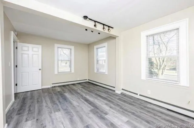 a view of an empty room with wooden floor and a window