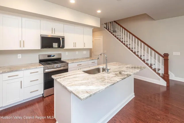 a kitchen with stainless steel appliances granite countertop a kitchen island a stove a sink and a refrigerator